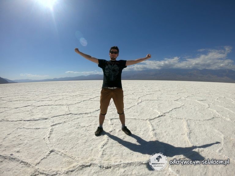 Maciek z rozłożonymi rękami na białej solnej równinie Badwater Basin w Dolinie Śmierci
