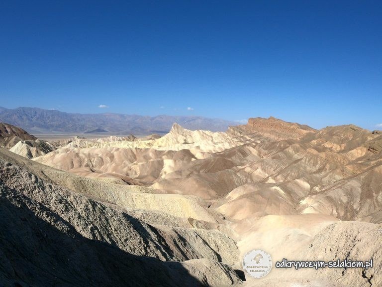 Jasne erozyjne formacje skalne ze spiczastym szczytem Manly Beacon widziane z Zabriskie Point