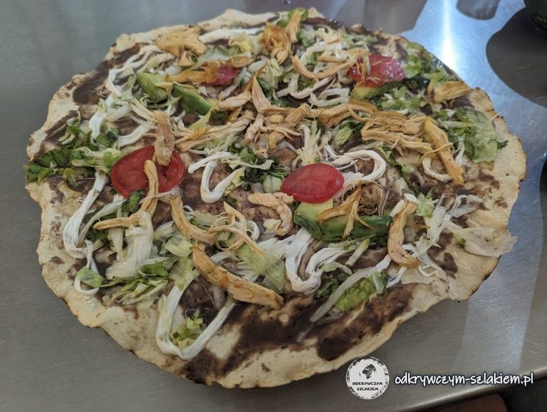 Una tlayuda, una gran tortilla crujiente con pasta de frijol negro, pollo, lechuga, tomate y aguacate, para comer en Oaxaca
