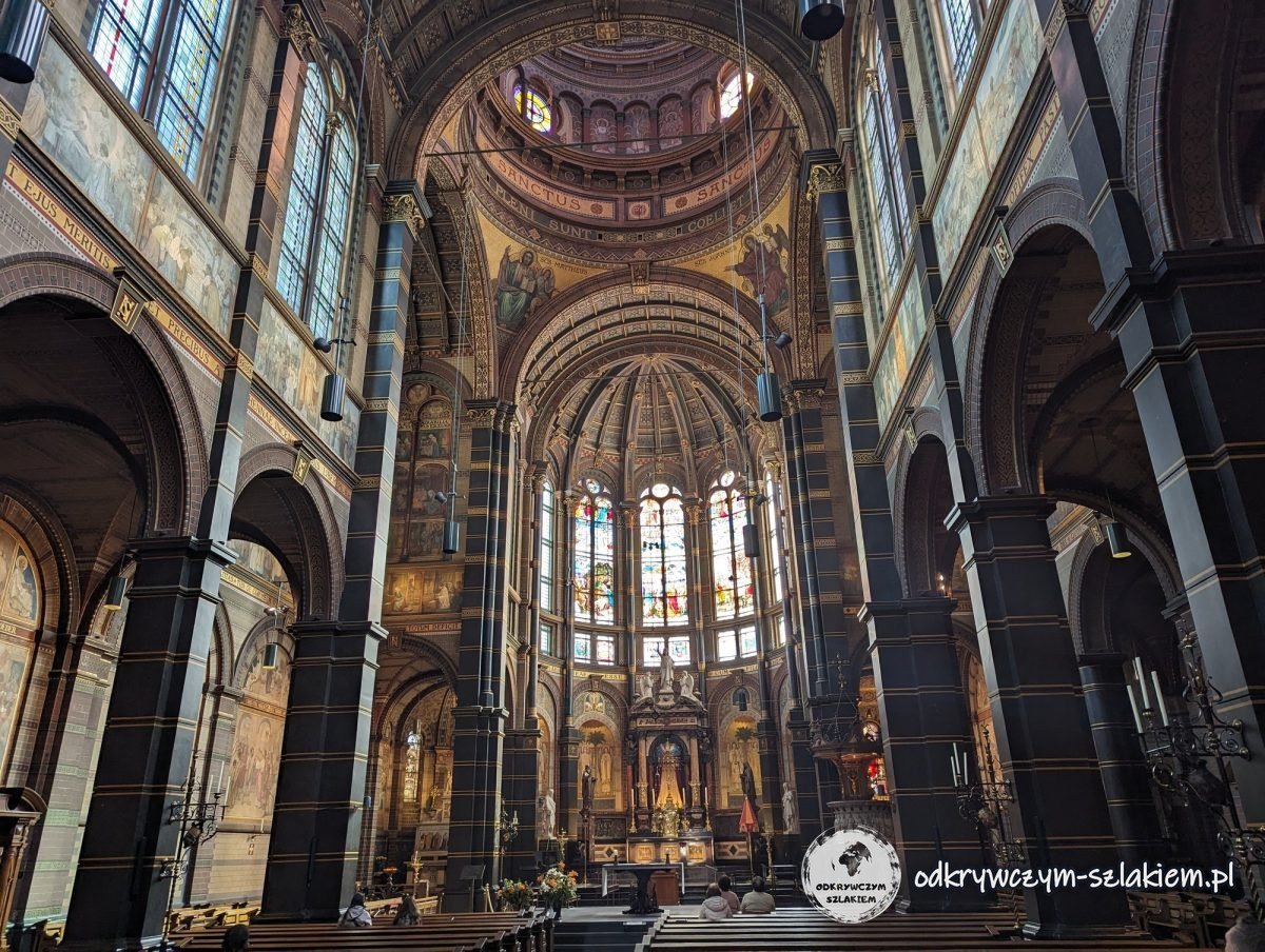 The interior of St Nicholas Basilica in Amsterdam with columns, paintings and stained glass in the choir