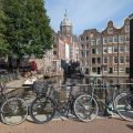 El canal Oudezijds Voorburgwal en Ámsterdam con bicicletas en el puente, casas con frontones y la cúpula de la basílica de San Nicolás