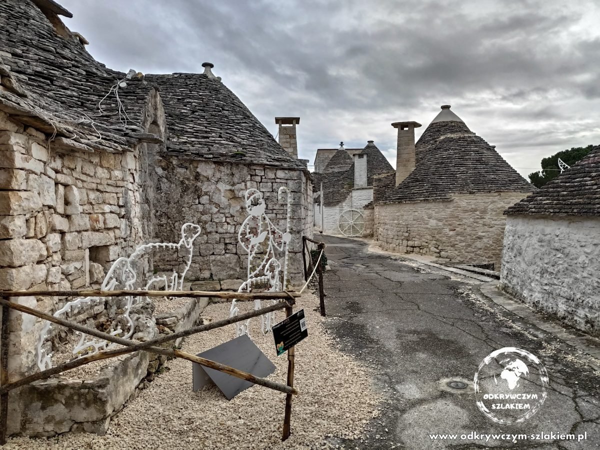 Świąteczne figury z lampek ustawione przy kamiennych trullach w Alberobello