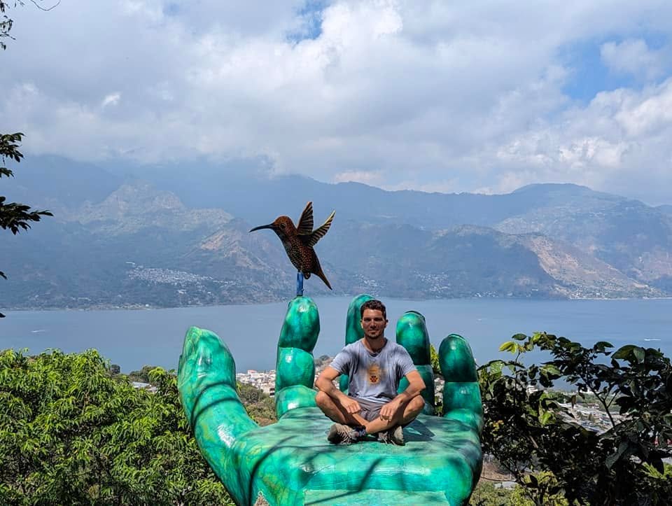 Na wielkiej zielonej dłoni z kolibrem w punkcie widokowym Nido del Colibrí, w tle jezioro Atitlán