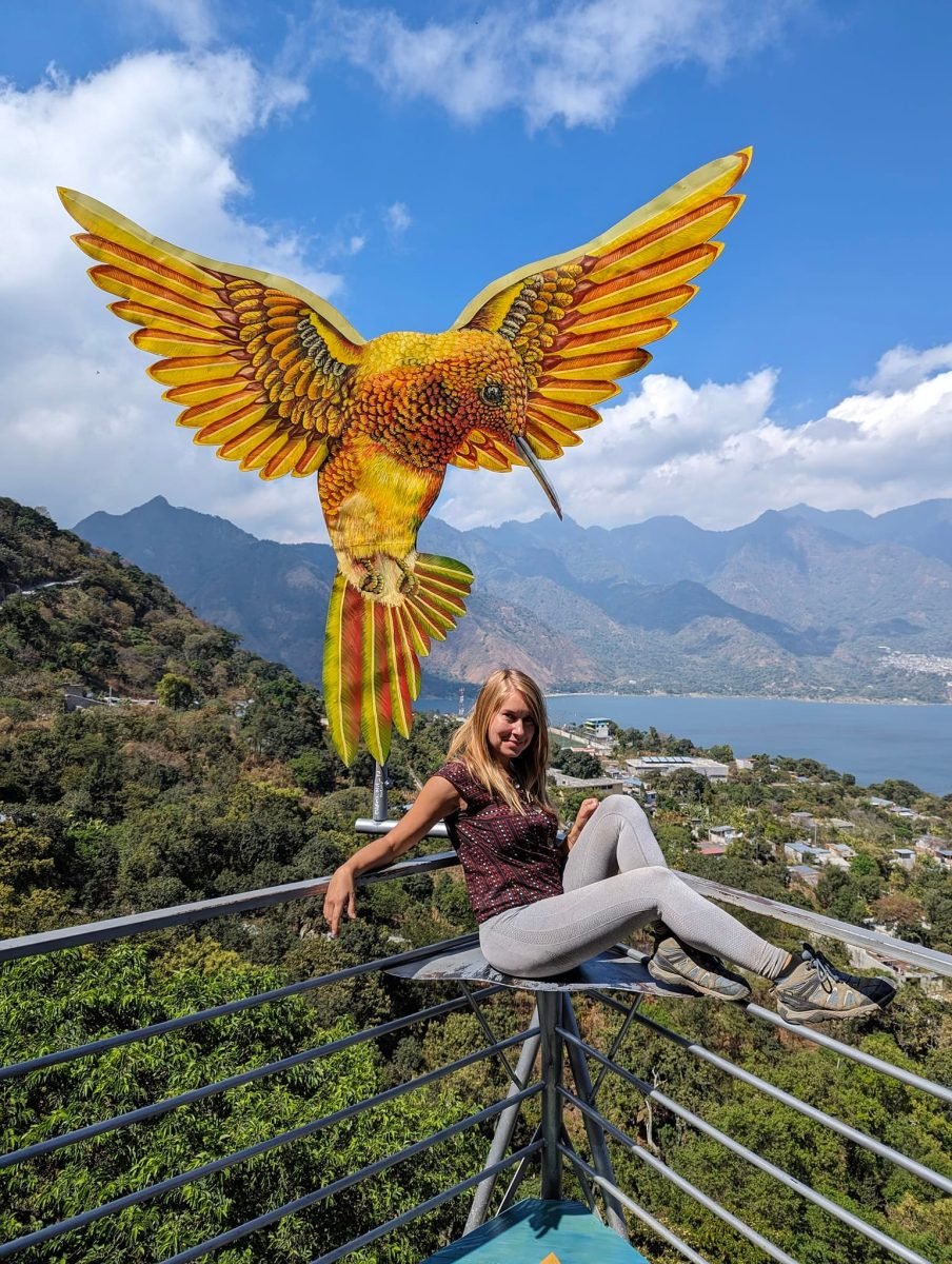 Patrycja pod wielką rzeźbą kolibra w punkcie widokowym Nido del Colibrí, w dole San Pedro La Laguna i jezioro