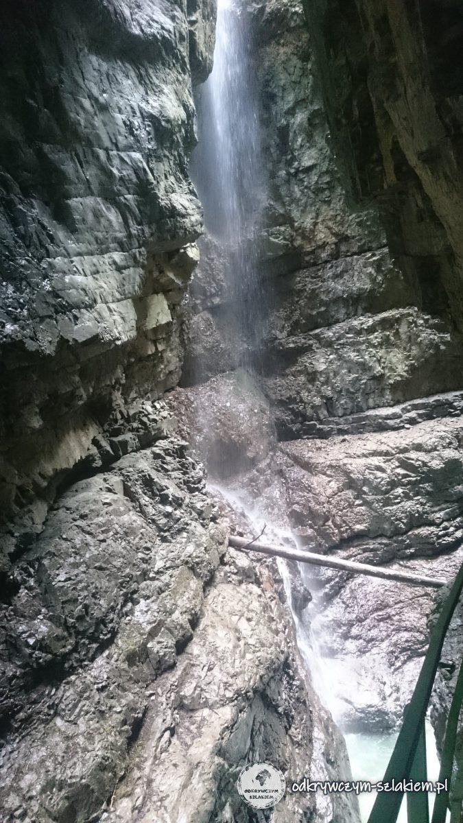 Ein Wasserfall eines Seitenbachs fließt über die Felsen in die Breitachklamm, daneben das Geländer des Weges