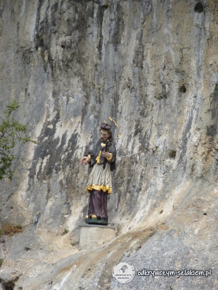 Eine bunte Figur des heiligen Johannes Nepomuk auf einem Felsvorsprung in der Wand des Donaudurchbruchs