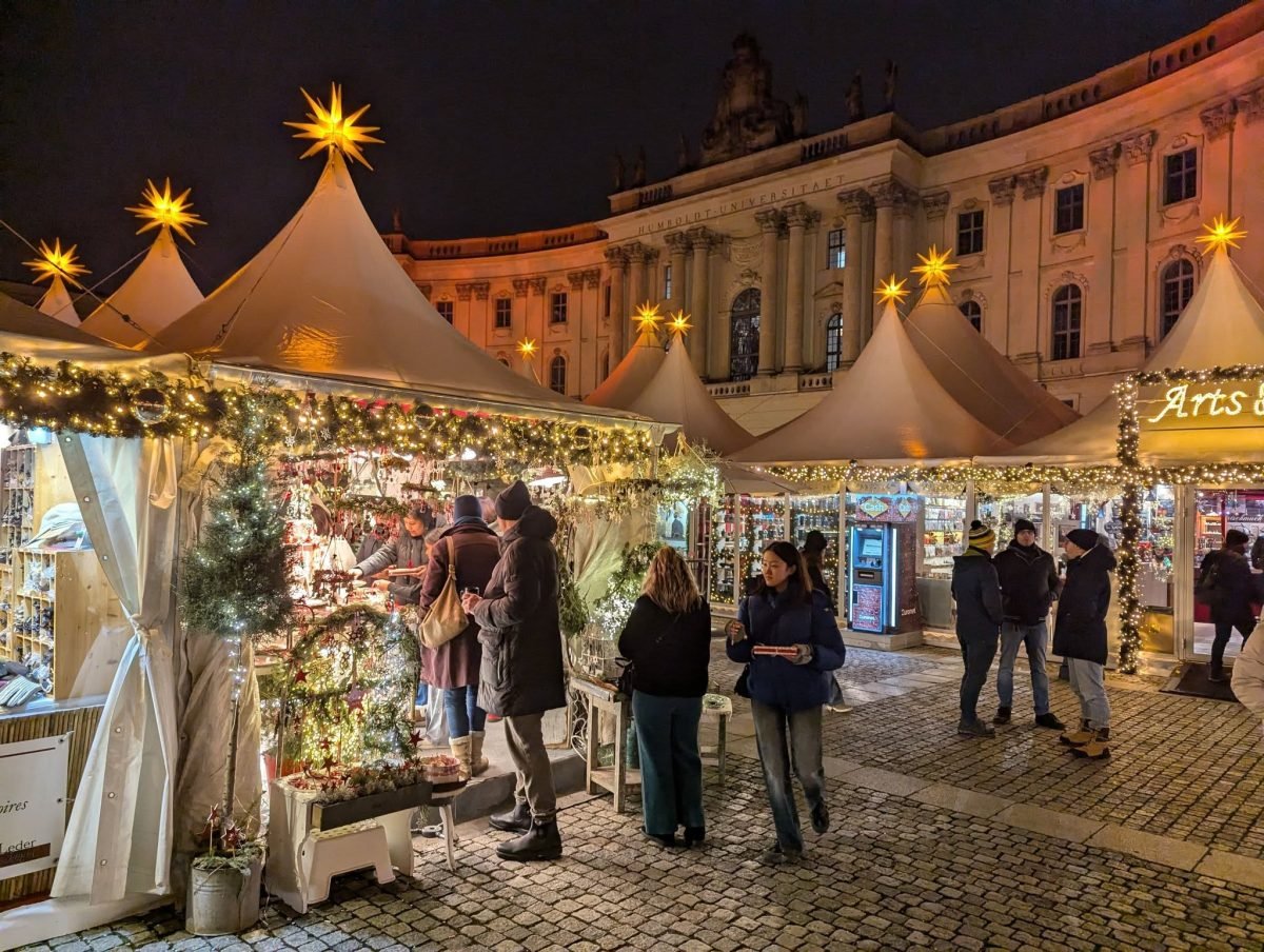 Jarmark świąteczny z białymi namiotami i gwiazdami na placu w centrum Berlina, wieczorem