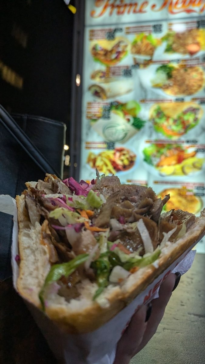 Döner kebab w bułce na tle menu budki z jedzeniem
