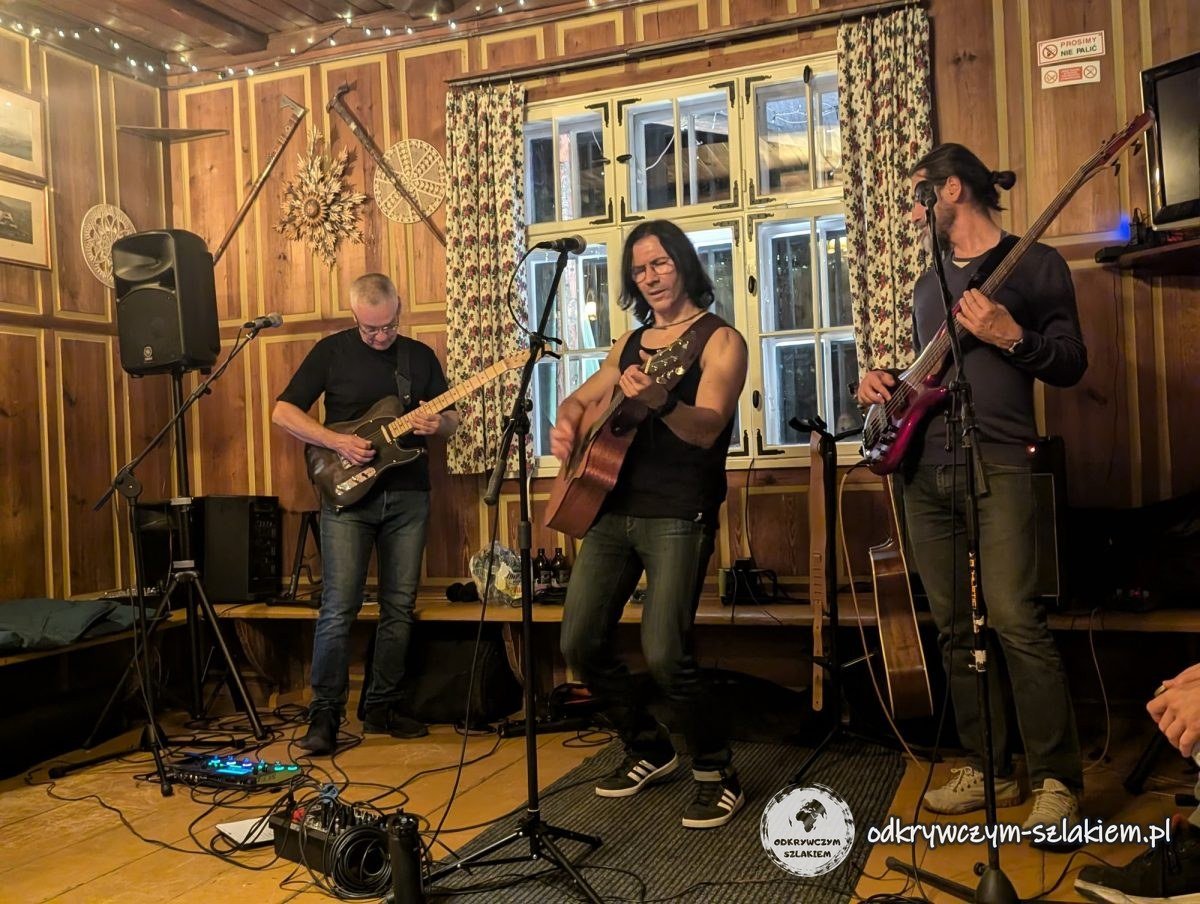 Tres músicos con guitarras dan un concierto en la sala de madera del refugio Soszów