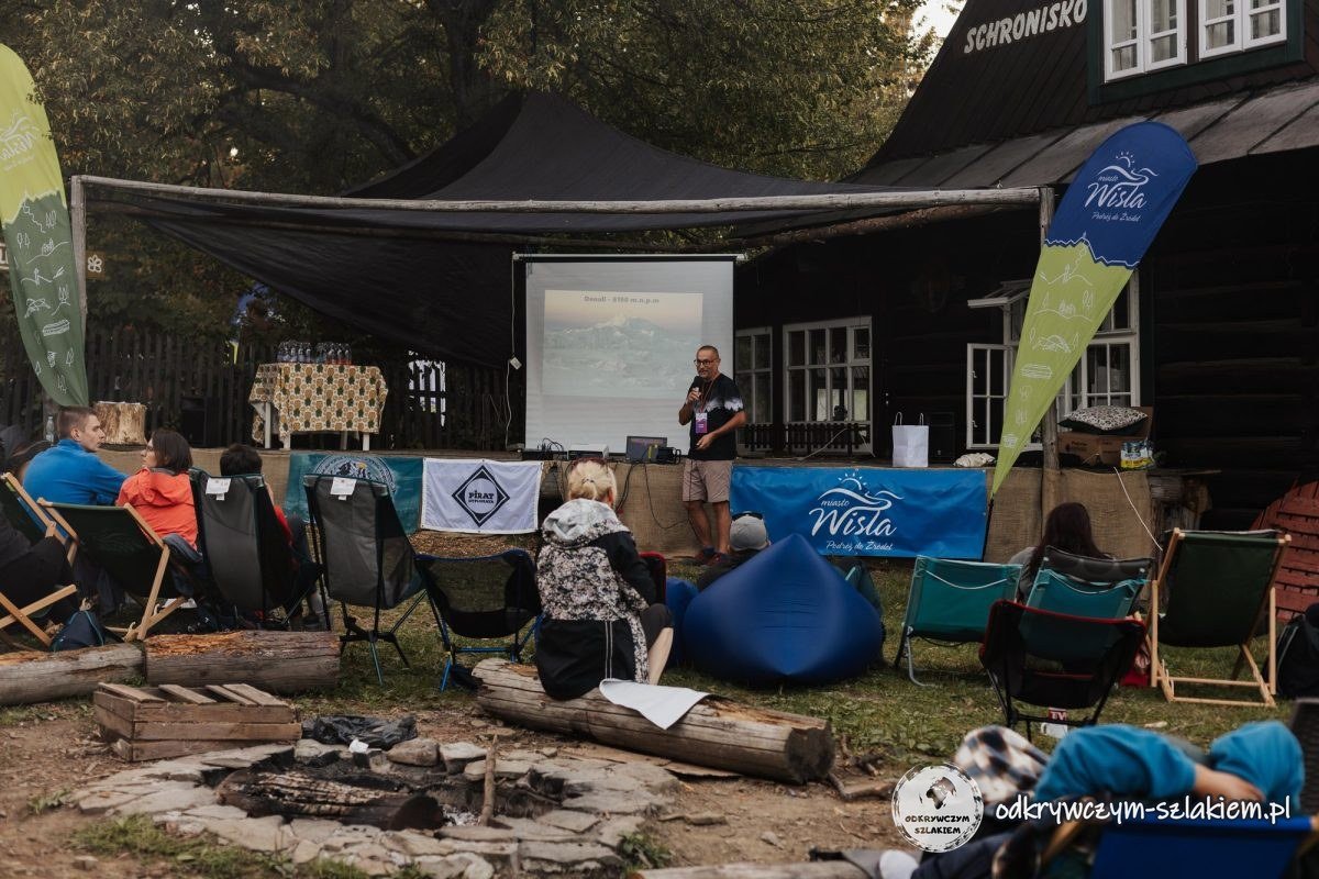 Escenario al aire libre con pantalla y público en tumbonas frente al refugio Soszów