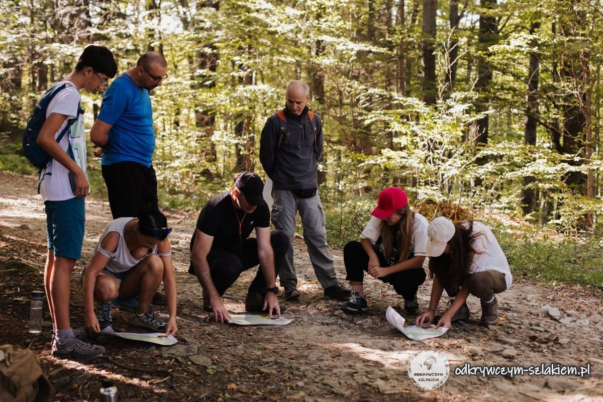 Asistentes al festival inclinados sobre mapas extendidos en un camino del bosque