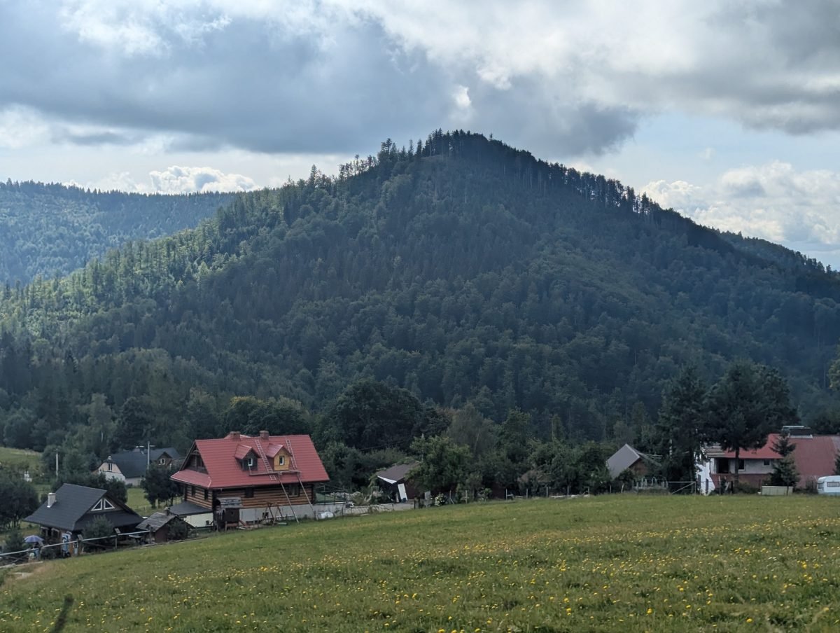 Cumbre boscosa sobre un prado y casas en los Beskides de Silesia cerca de Wisła