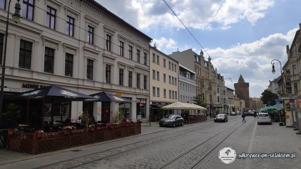 Ulica Steinstraße w Brandenburg an der Havel z ogródkami restauracji i wieżą Steintorturm na końcu