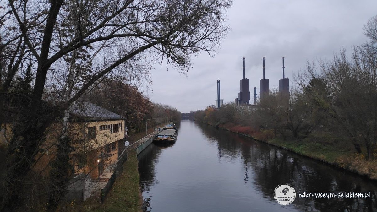 Teltowkanal z zacumowaną barką, w oddali kominy elektrociepłowni