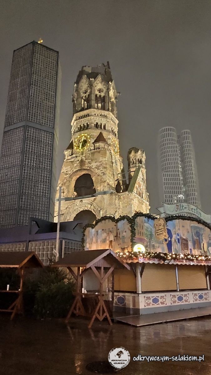 La torre en ruinas de la Iglesia Memorial sobre las casetas del mercado navideño de noche