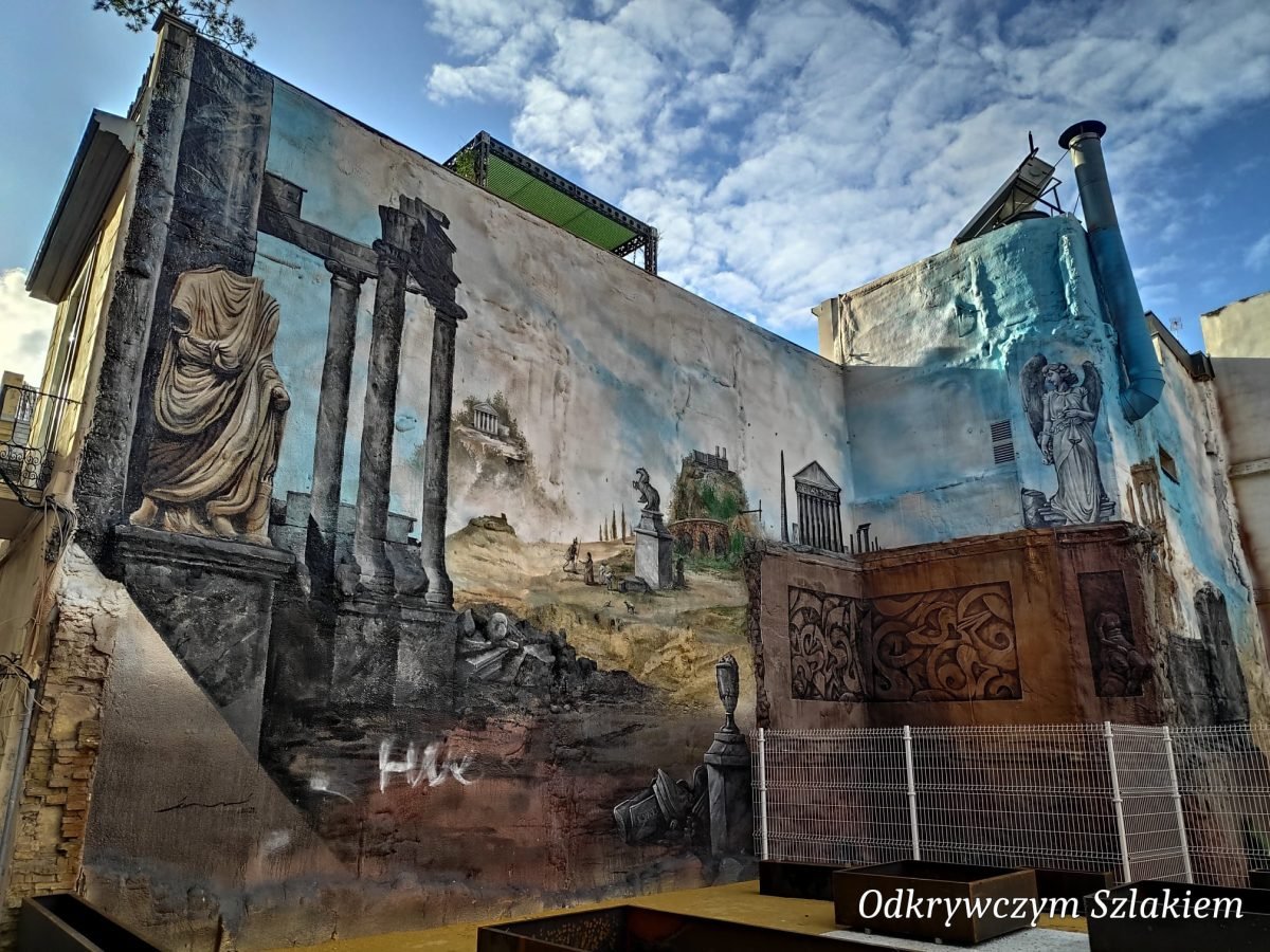 Mural z ruinami rzymskich kolumn na ścianie kamienicy w Kartagenie