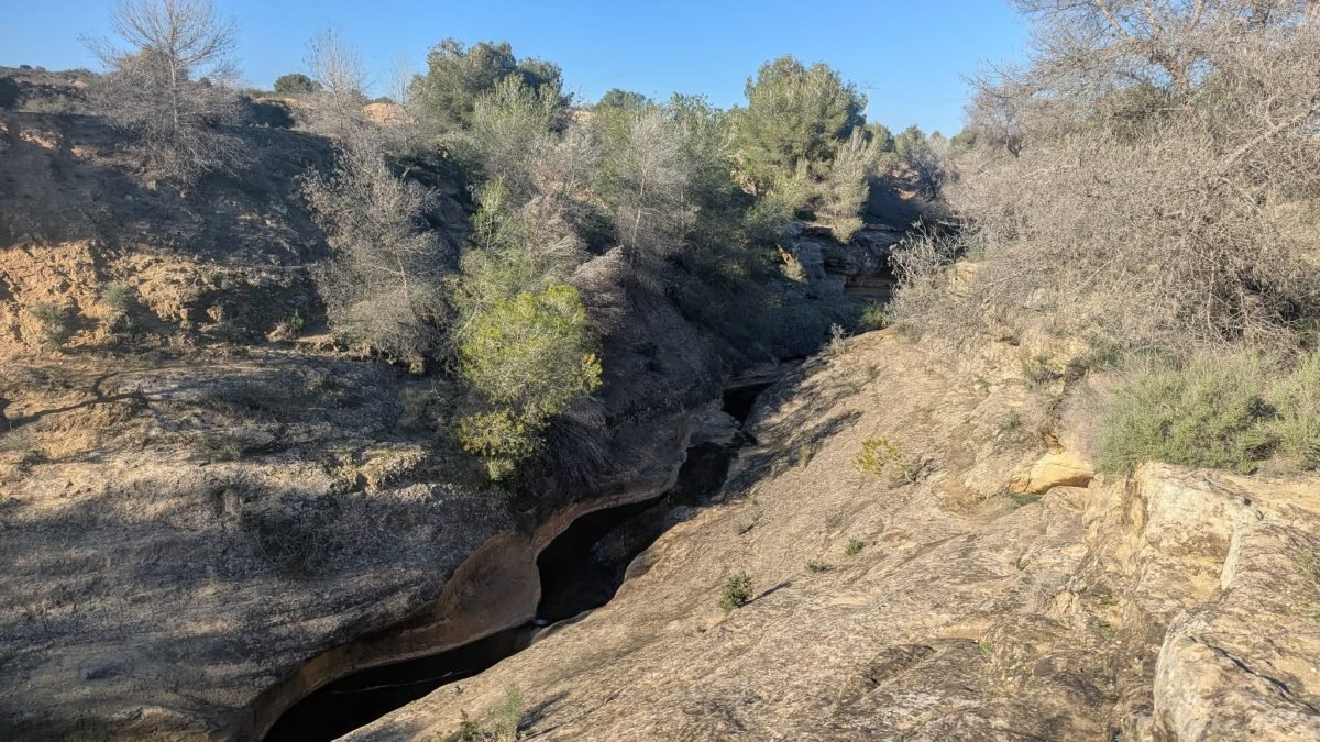 Wąska skalna rozpadlina wśród zarośli na szlaku La Caldera del Gigante
