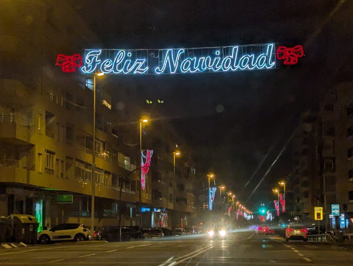 Świetlny napis Feliz Navidad nad ulicą w Torrevieja wieczorem