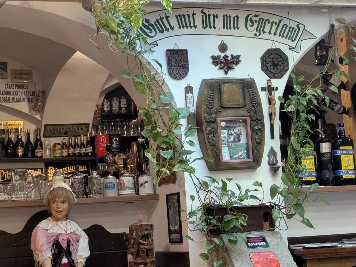 Wnętrze lokalu w Karlowych Warach z butelkami Becherovki i napisem Gott mit dir mei Egerland