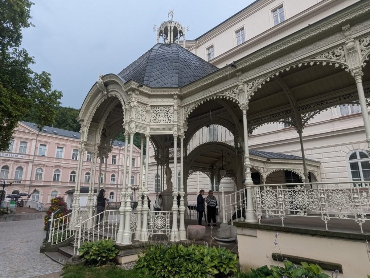 Biała, ażurowa altana przy kolumnadzie w Karlowych Warach