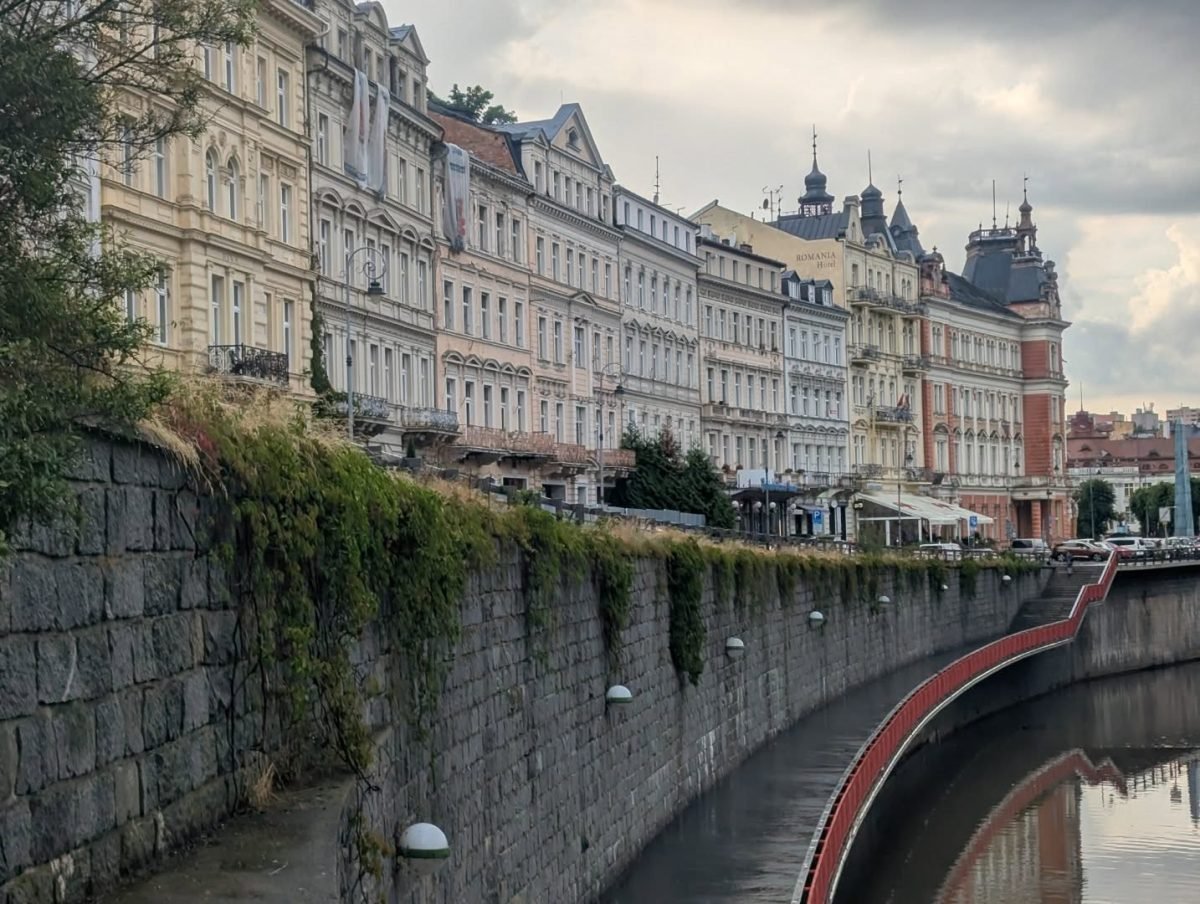 Kamienny mur nad rzeką Teplá i rząd kamienic na nabrzeżu w Karlowych Warach