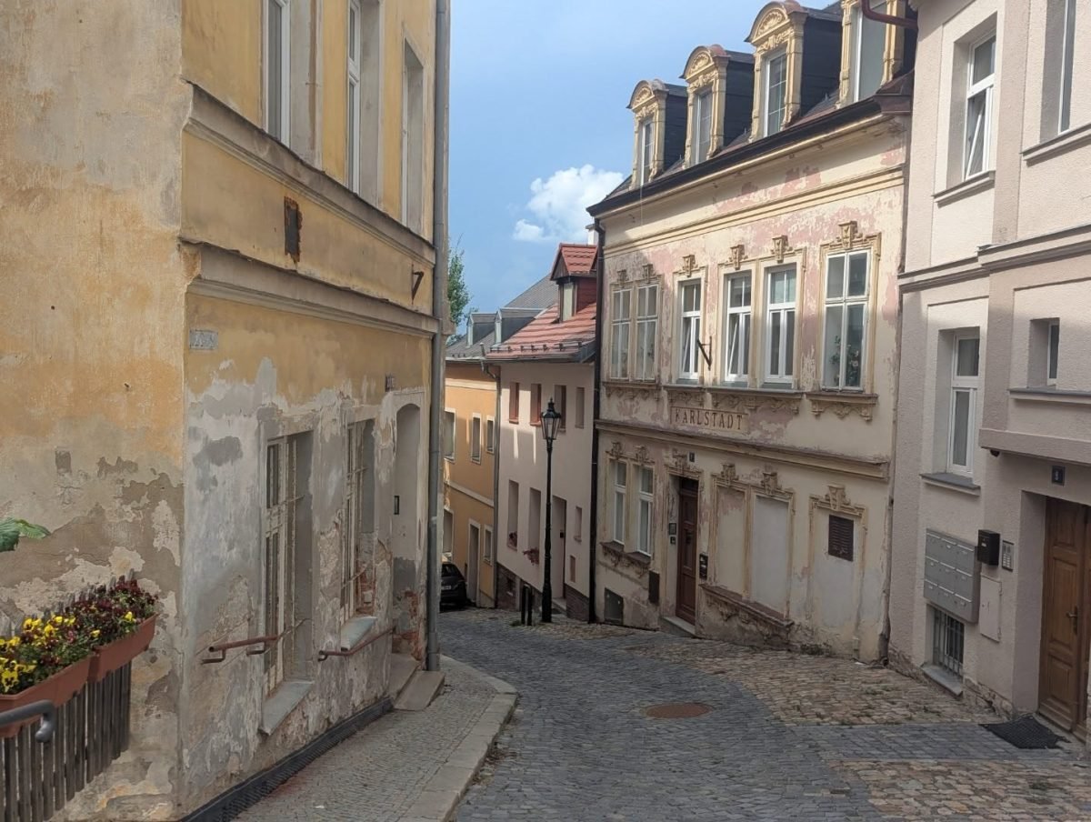 Wąska, brukowana uliczka między starymi kamienicami w Karlowych Warach