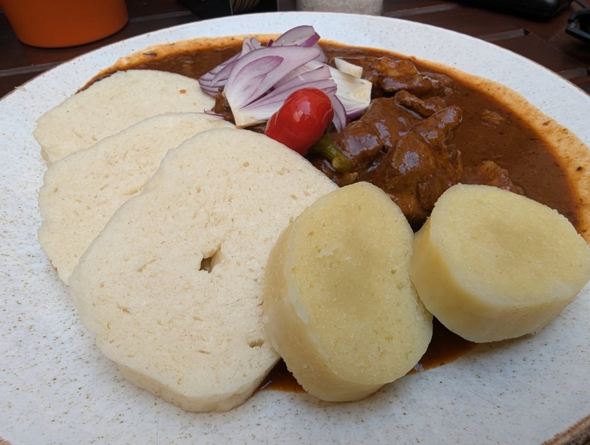 Czeskie knedliki z gulaszem i cebulą na talerzu w praskiej restauracji