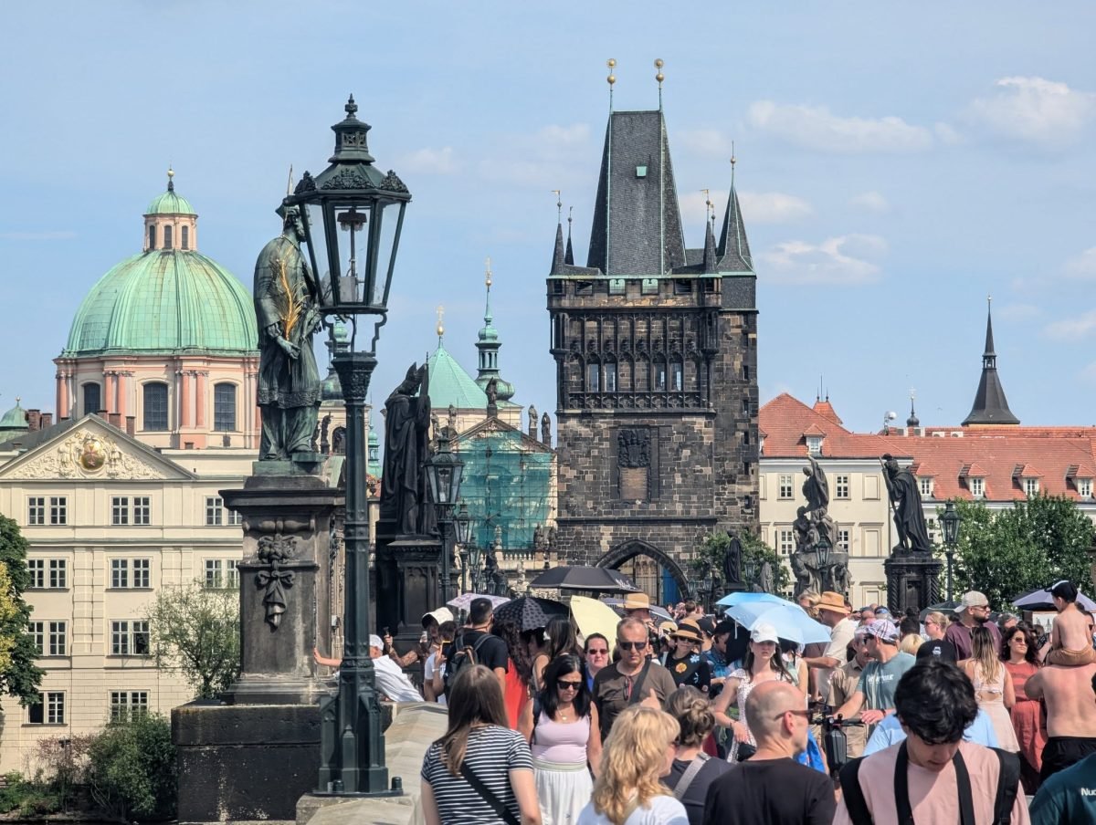Tłum turystów na Moście Karola, w tle Staromiejska Wieża Mostowa i kopuła kościoła