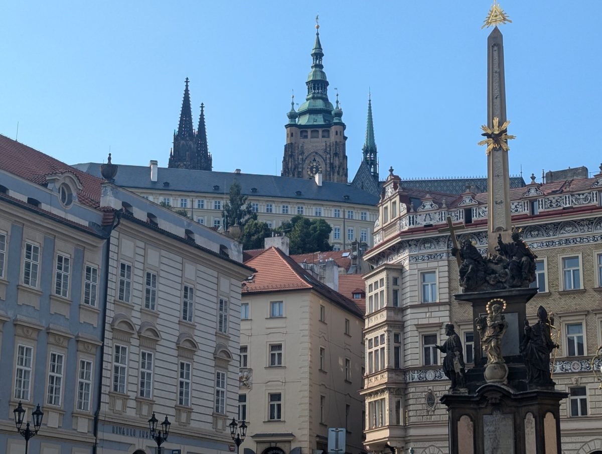 Plac Małostrański w Pradze z kolumną morową, nad dachami wieże katedry św. Wita