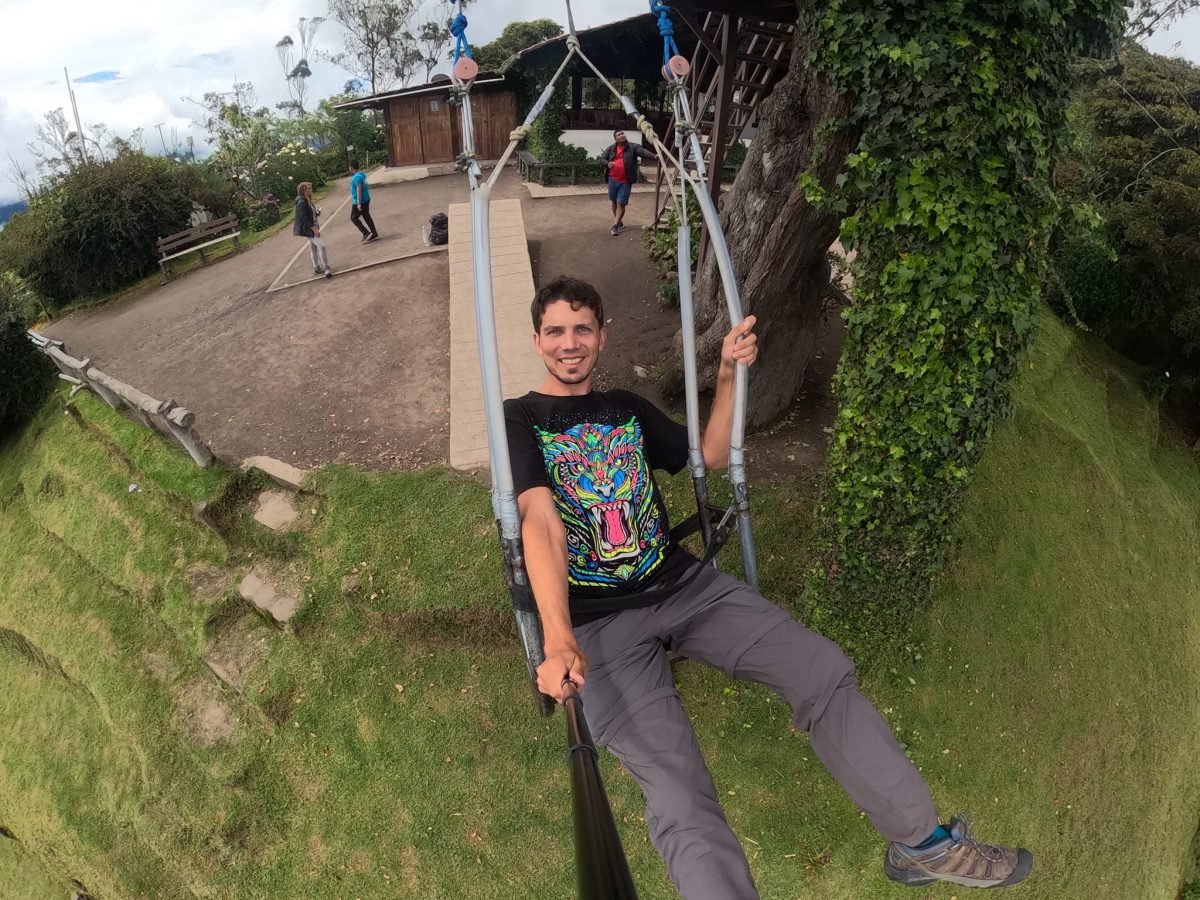 Maciek na huśtawce w La Casa del Árbol sfotografowany z bliska kamerką, w tle trawnik i drewniane budynki