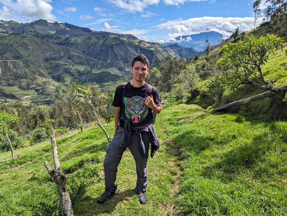 Maciek na zielonej ścieżce trzeciego dnia trekkingu, w tle góry i chmury