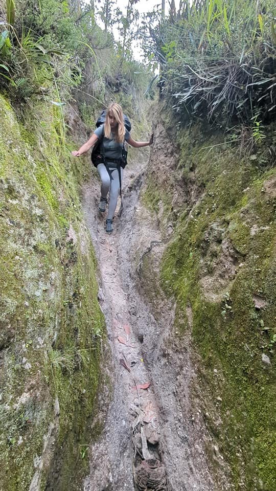 Patrycja schodzi wąskim, wypłukanym rowem między zboczami na szlaku do Isinliví