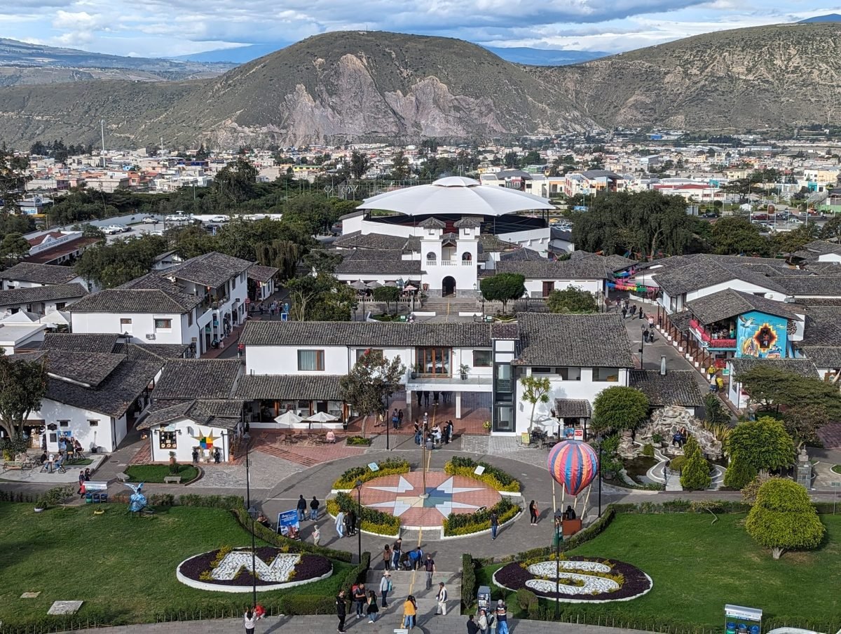 Widok z pomnika Mitad del Mundo na miasteczko, różę wiatrów i litery N i S na trawnikach