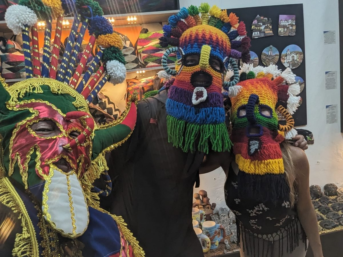 Trzy osoby w maskach Aya Huma i w stroju z pióropuszem podczas free walking tour w Quito