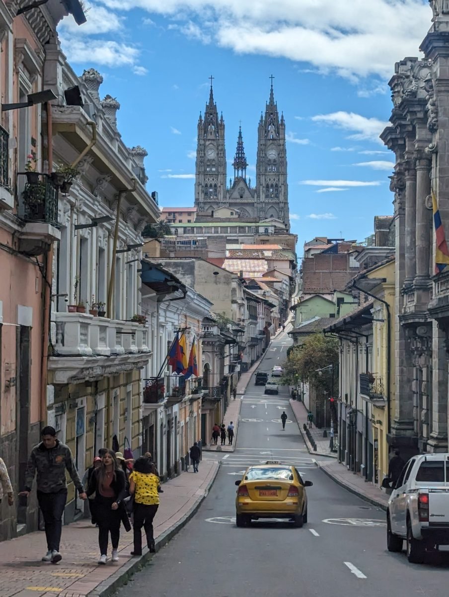 Stroma uliczka starego miasta w Quito z wieżami Bazyliki Głosowania Narodowego w tle