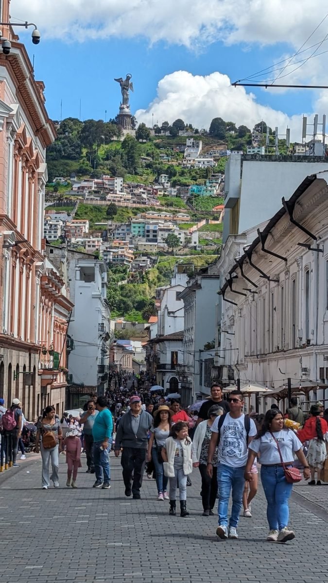 Deptak na starym mieście w Quito z figurą Matki Bożej na wzgórzu El Panecillo w tle