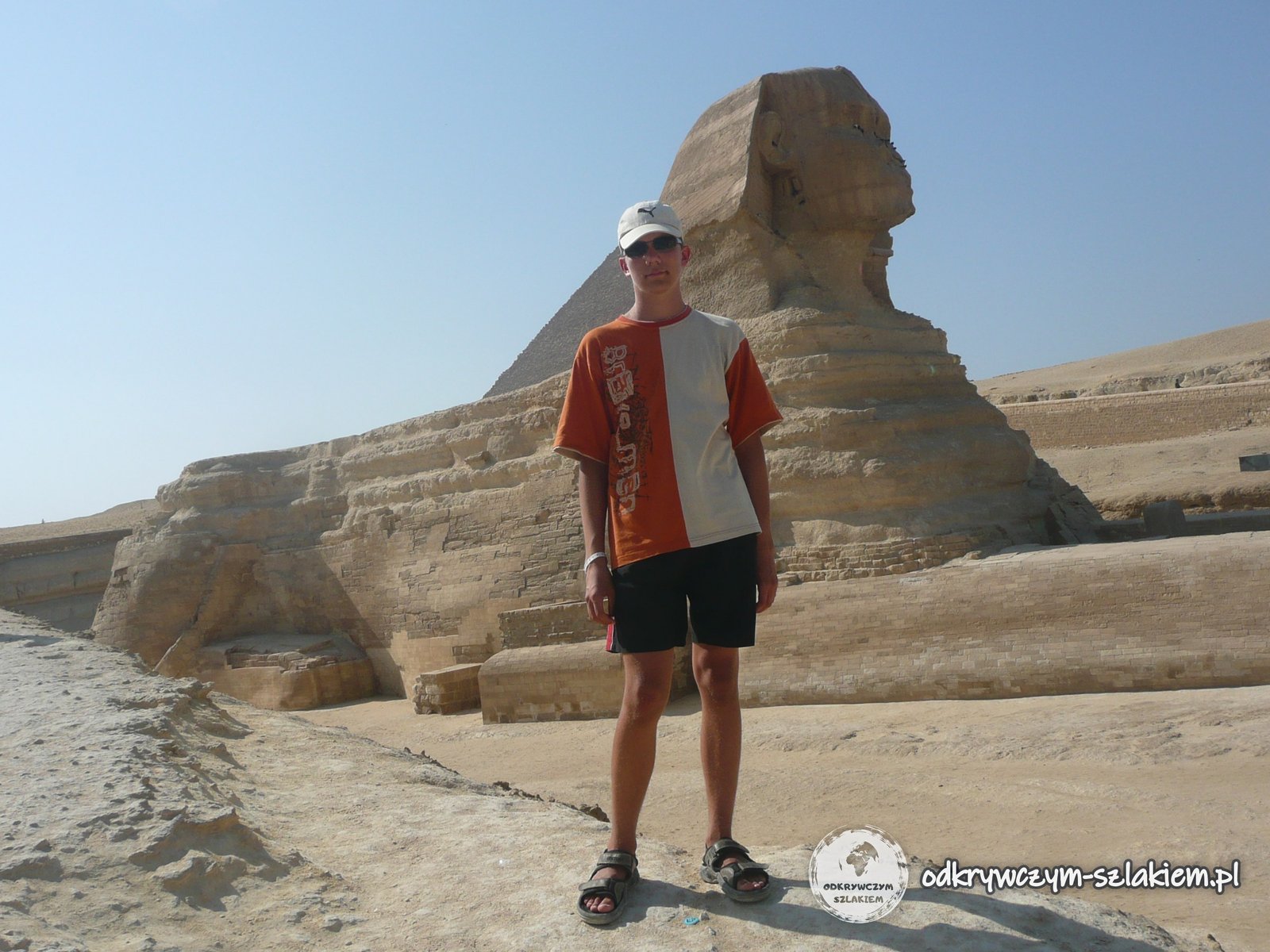 Ein Tourist vor der Großen Sphinx von Gizeh, dahinter eine Pyramide