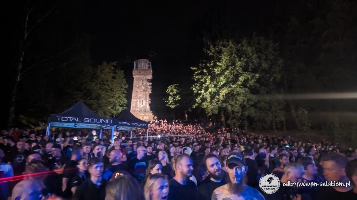Menge vor der Materiafest-Bühne bei Nacht, dahinter der angestrahlte Bismarckturm in Szczecinek