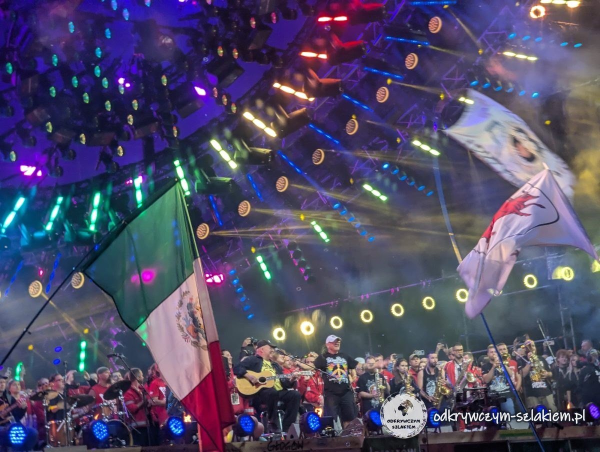 Nächtliches Finale des Pol'and'Rock Festival 2024 – Musiker auf der Großen Bühne, Flammen und Fahnen