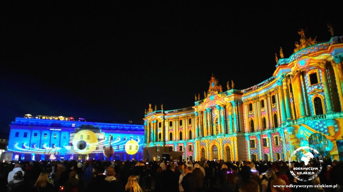 Projekcja na Wydziale Prawa Uniwersytetu Humboldtów i Hotelu de Rome przy Bebelplatz, przed nimi tłum (Festival of Lights 2022)