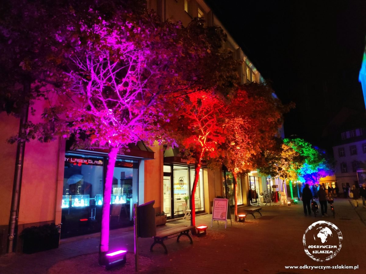 Drzewa podświetlone na różowo i czerwono przy uliczce Am Nußbaum w Nikolaiviertel – Tree of Lights (Festival of Lights 2022)