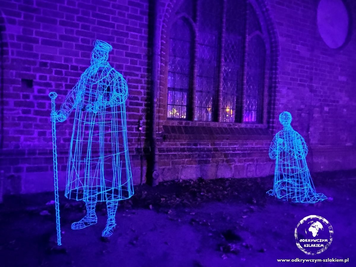 Świetliste, druciane postacie w dawnych strojach przy kościele św. Mikołaja w Nikolaiviertel – Ghostly Guests (Festival of Lights 2022)