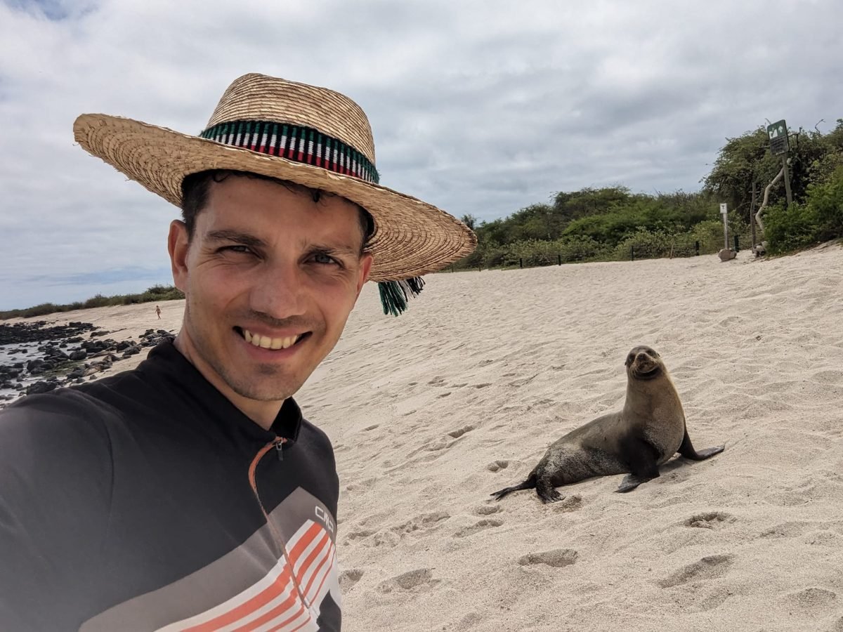 Maciek w kapeluszu na plaży z lwem morskim na San Cristóbal