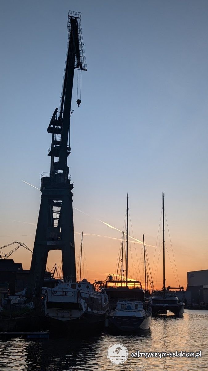 Die Silhouette eines alten Werftkrans und Jachten am Kaiserlichen Dock in Danzig bei Sonnenuntergang