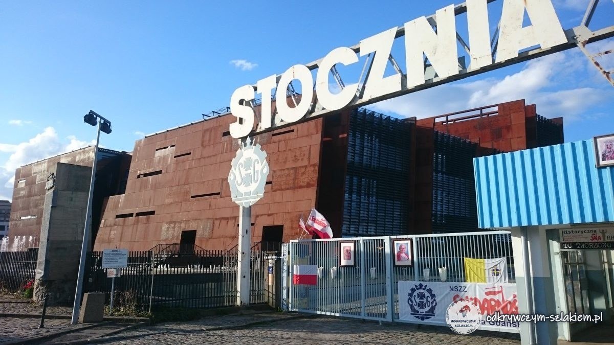 Tor Nr. 2 der Danziger Werft mit einem Porträt von Johannes Paul II. und einem Solidarność-Banner, dahinter das rostfarbene Europäische Solidarność-Zentrum