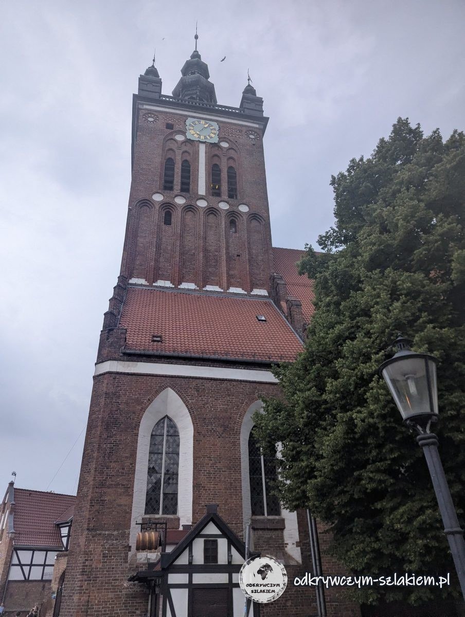 The brick tower of St Catherine's Church in Gdańsk with its clock, seen from below
