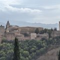 Alhambra na wzgórzu nad Grenadą, z cyprysami na pierwszym planie i pasmem Sierra Nevada w tle
