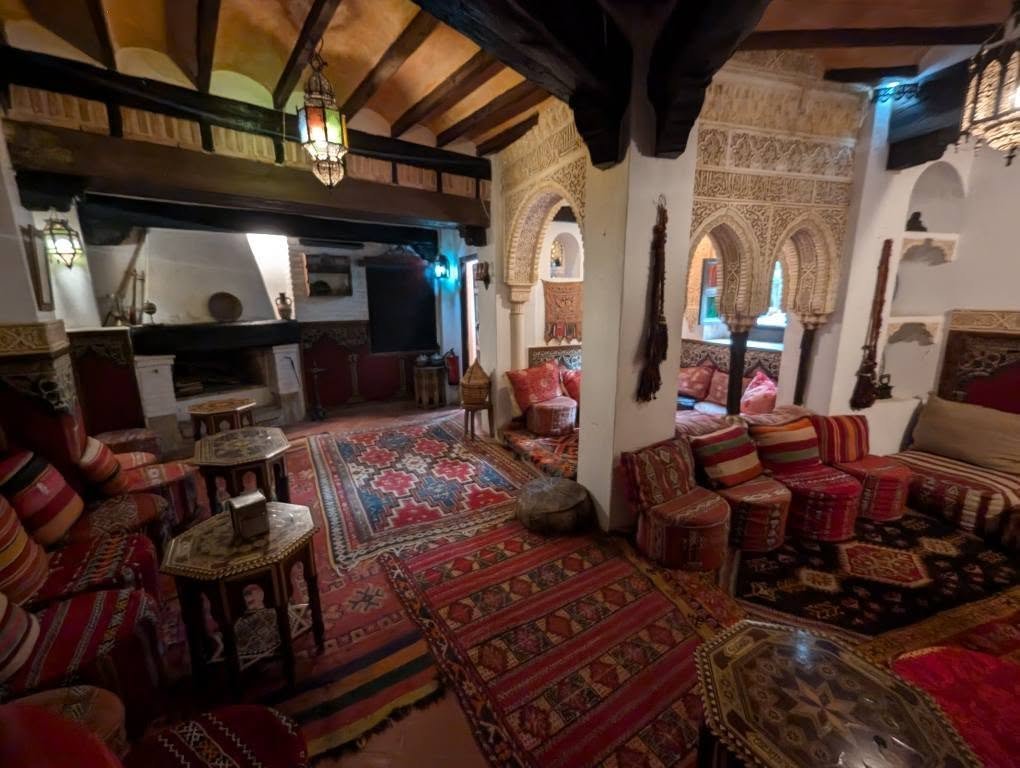 Salon w herbaciarni Carmen del Campillo z łukami zdobionymi stiukami, niskimi kanapami i kolorowymi dywanami