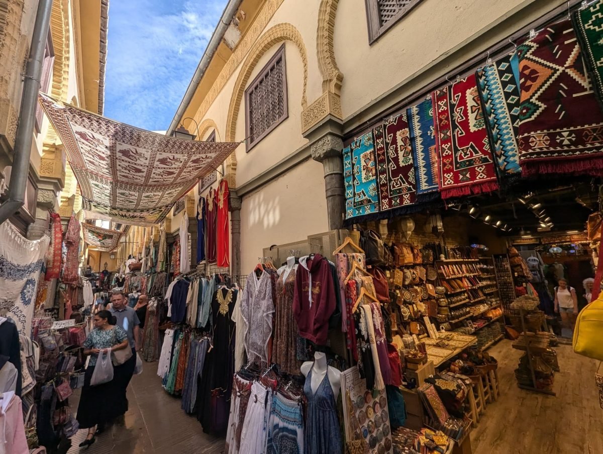 Kramy z dywanami, torbami i ubraniami w arabskim stylu w wąskiej uliczce w centrum Grenady