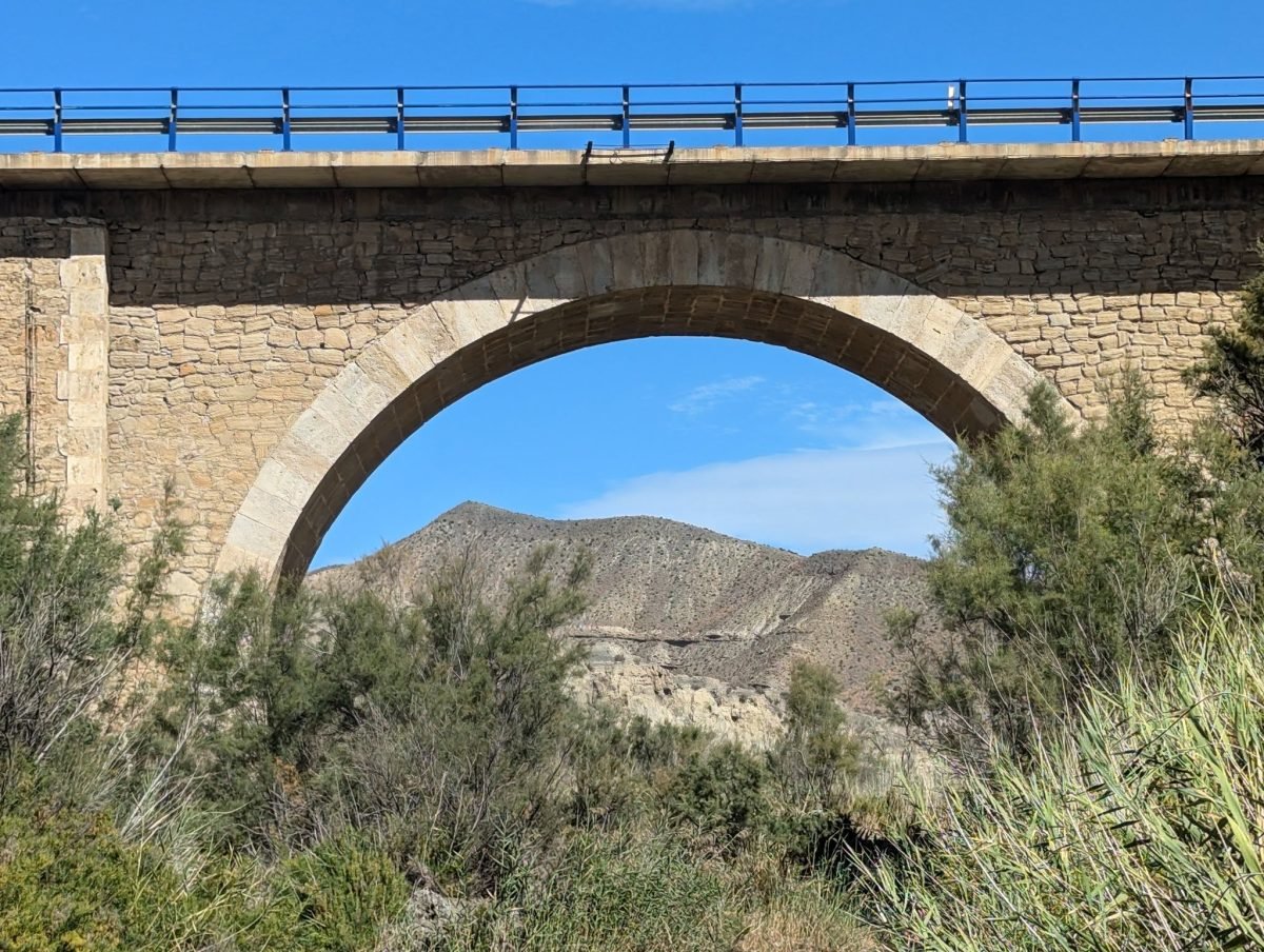 Kamienny most łukowy nad wąwozem na pustyni Tabernas, w prześwicie suche wzgórza